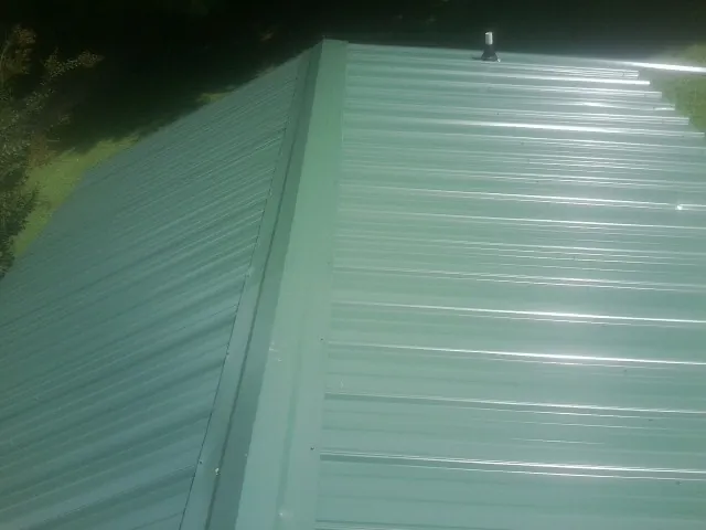 New green metal panels meeting at the ridge of a roof — Flat Roof Repair work by our crew in Westmoreland City