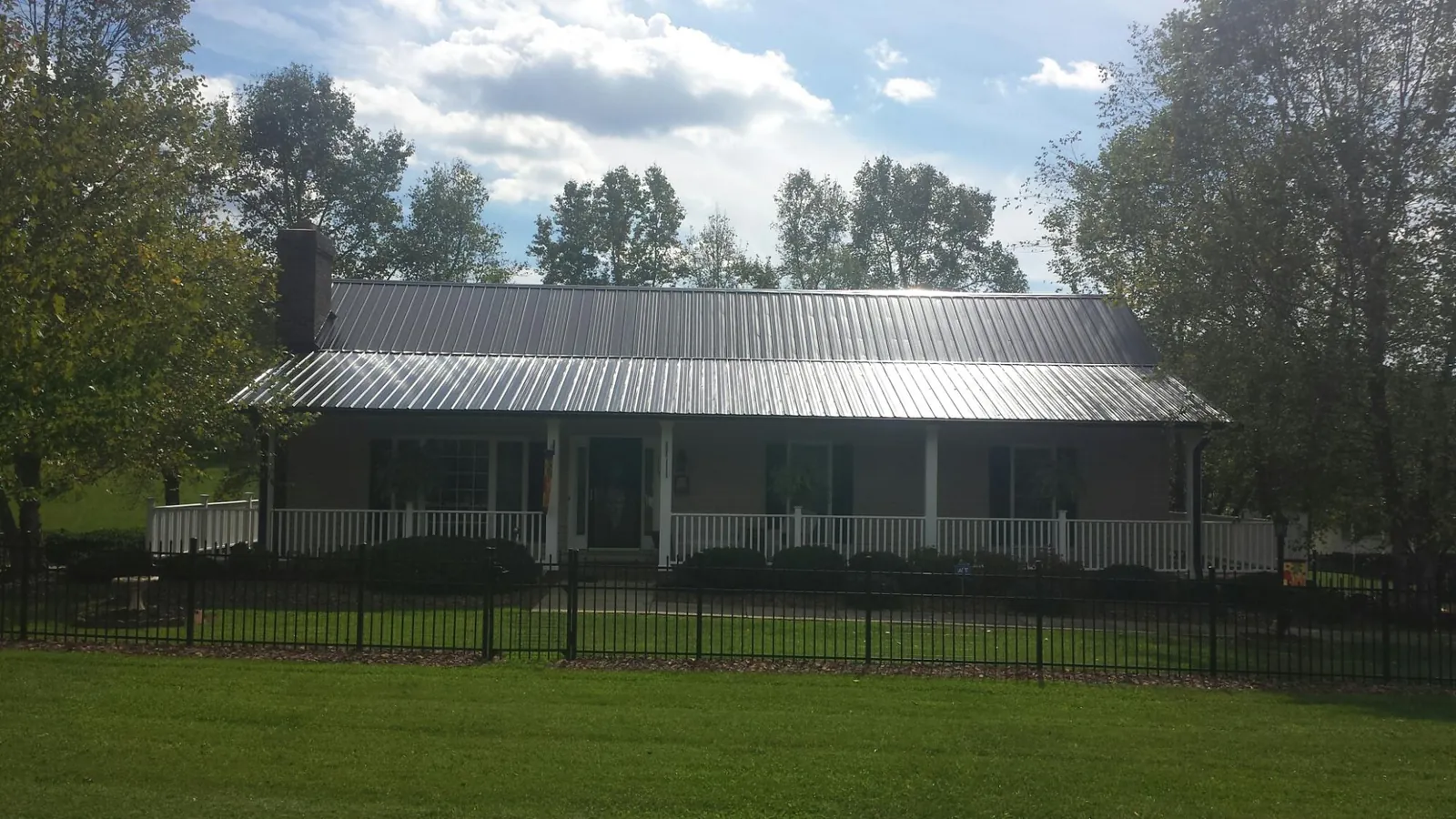 Gray metal roof on a brick ranch with a full width front porch — Gutter Guard Installation work by our crew in Westmoreland City