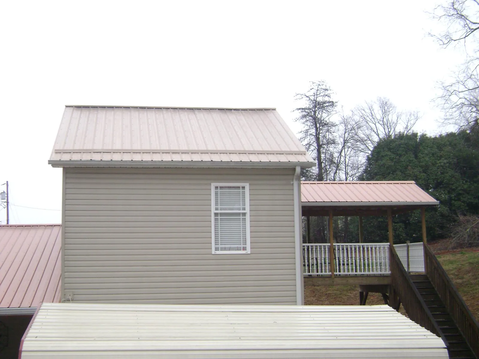 Tan metal roofs on a two story addition and attached porch, from a Roof Replacement job in Westmoreland City