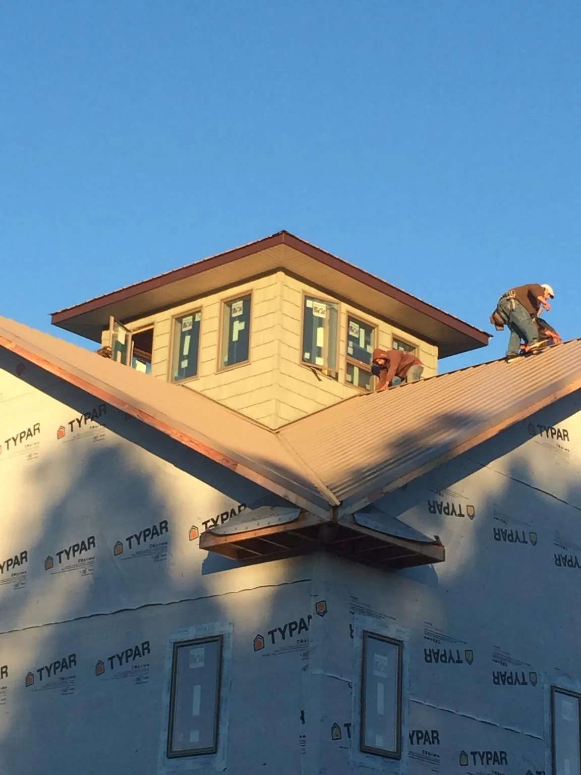 Roofers working around a rooftop cupola on a new metal roof at sunset — Roof Waterproofing in Westmoreland City by Roofing Brothers